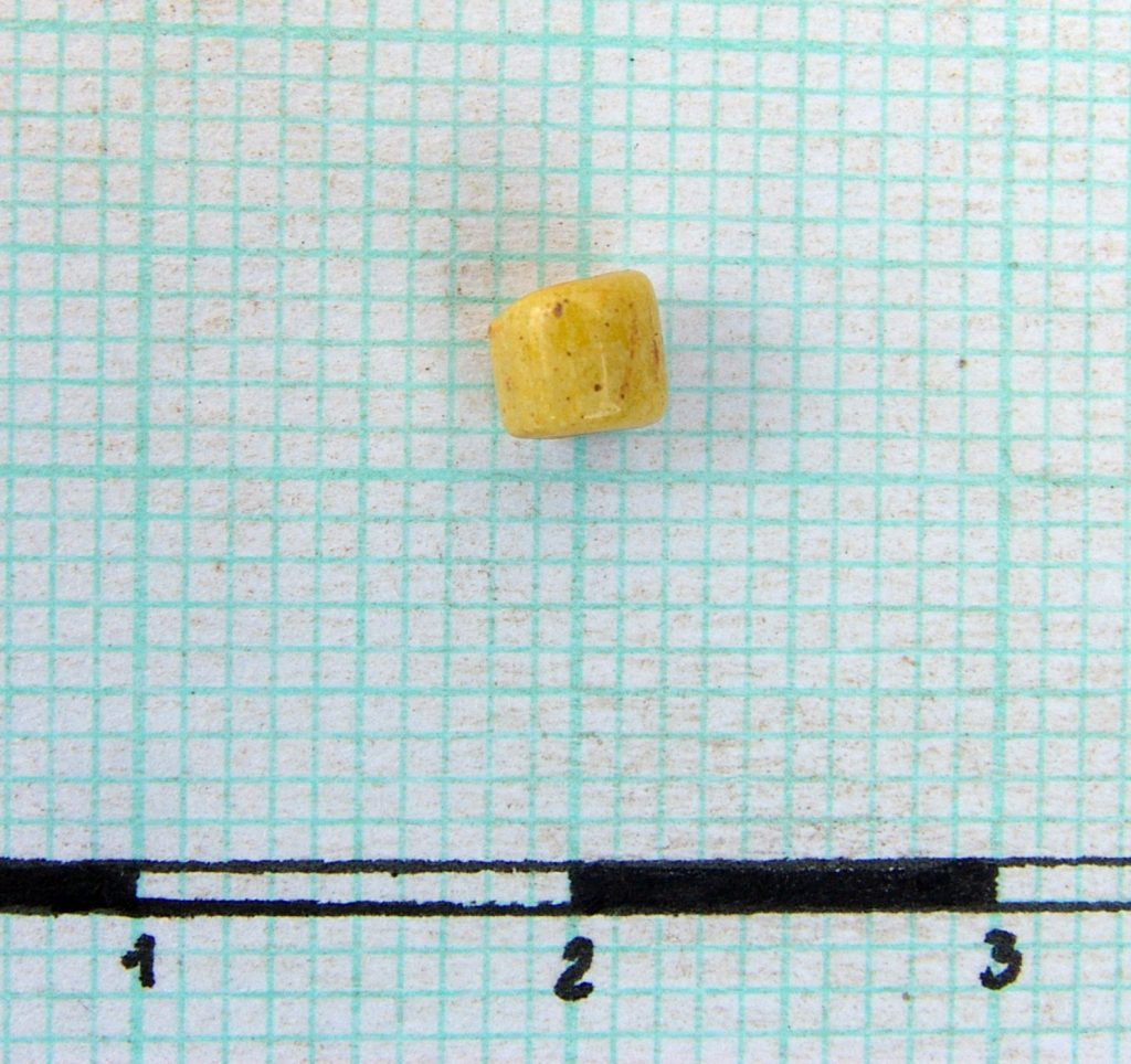 Fragment of bead made of yellow glass paste