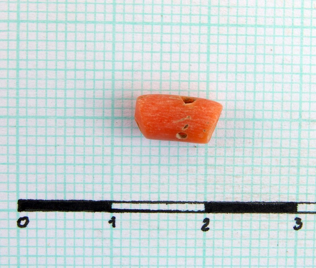 Light red stone (?) bead, more times perforated