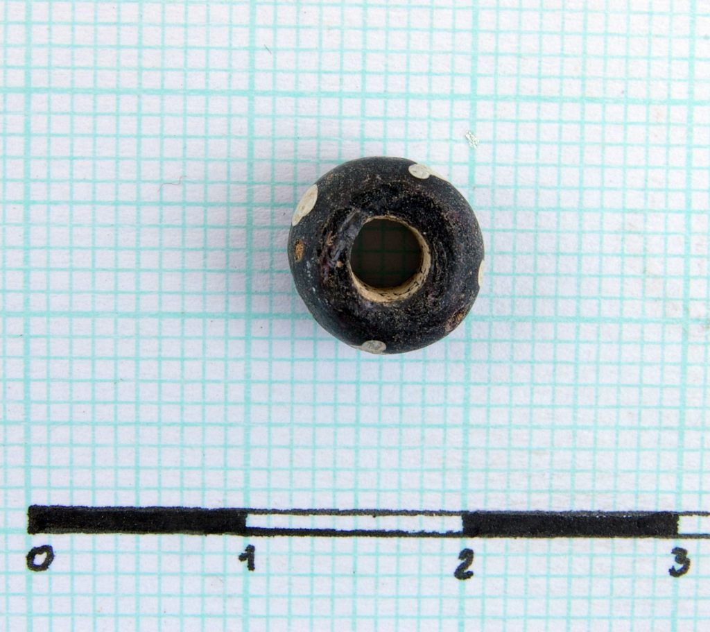 Black glass paste bead, perforated; with white dots